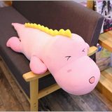 Pink dinosaur plush body pillow with a yellow ridge lying on a sofa