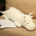 White and mint green dragon plush with antler-like horns on a sofa next to an open magazine.