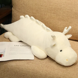 White and mint green dragon plush with antler-like horns on a sofa next to an open magazine.