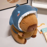 Capybara plush in a blue shark hood on a white table