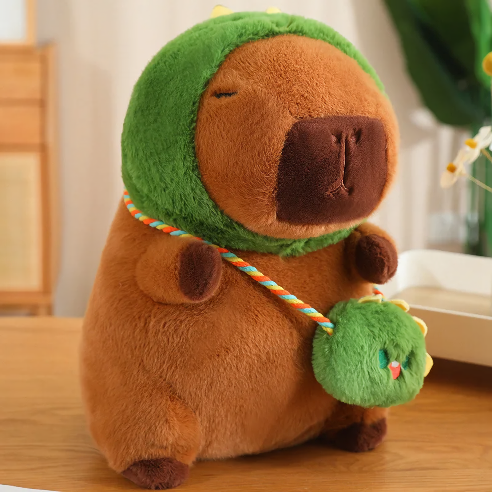 Capybara plush in a green dinosaur hood with a matching mini bag