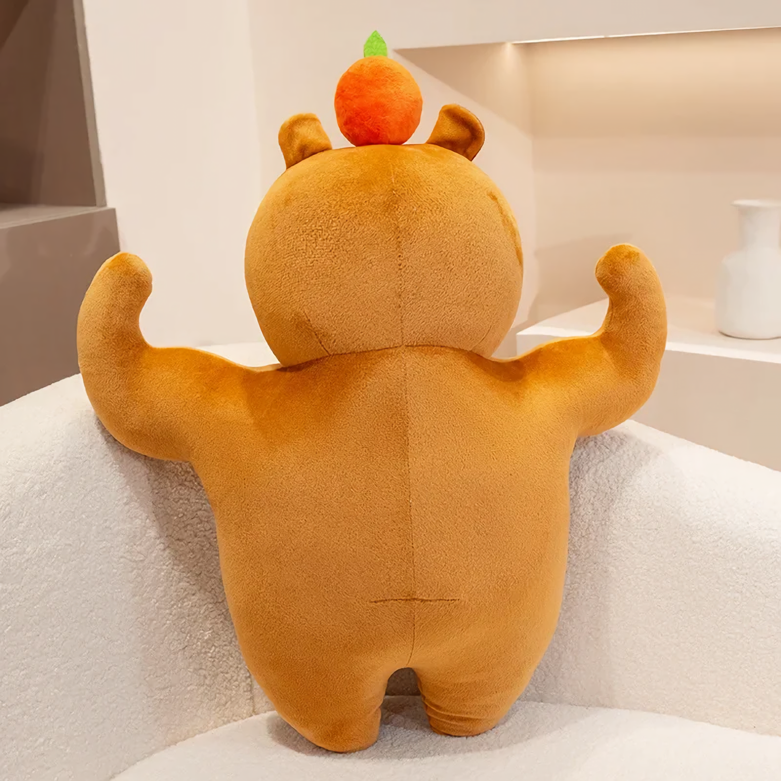 Back view of a muscle capybara plush with flexed arms on a sofa