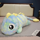 Rainbow Green dinosaur plush body pillow in blue and green tie dye with big eyes on a bed
