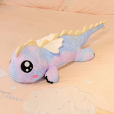 Rainbow purple and blue dragon plush with big eyes and wings on a pastel bed