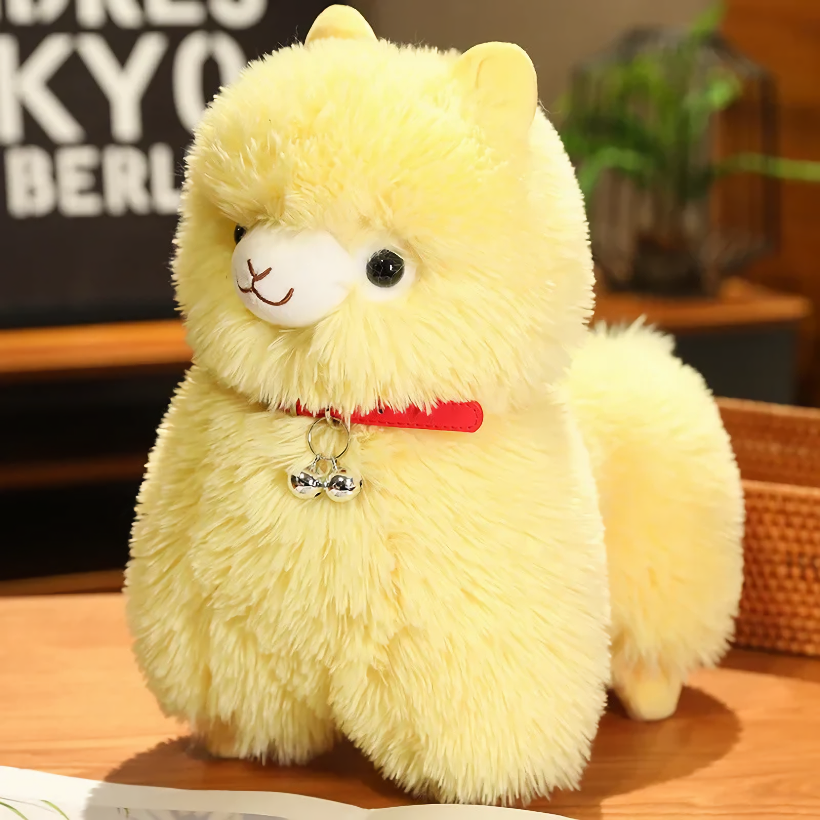 Yellow alpaca plush with a red bell collar and a fluffy tail