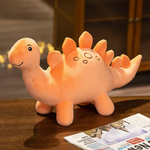 Orange Stegosaurus plush on a wooden table next to a newspaper.