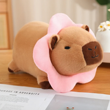 Capybara plush with a pink flower collar on a wooden table