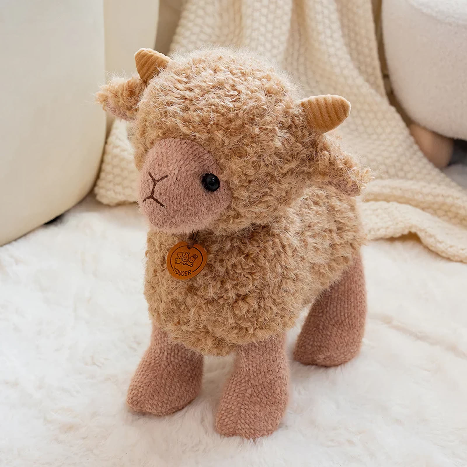 Brown curly lamb plush with tiny horns and an orange chest tag