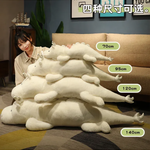 Woman sitting beside a stack of white and mint green dragon plush body pillows labeled with four lengths.