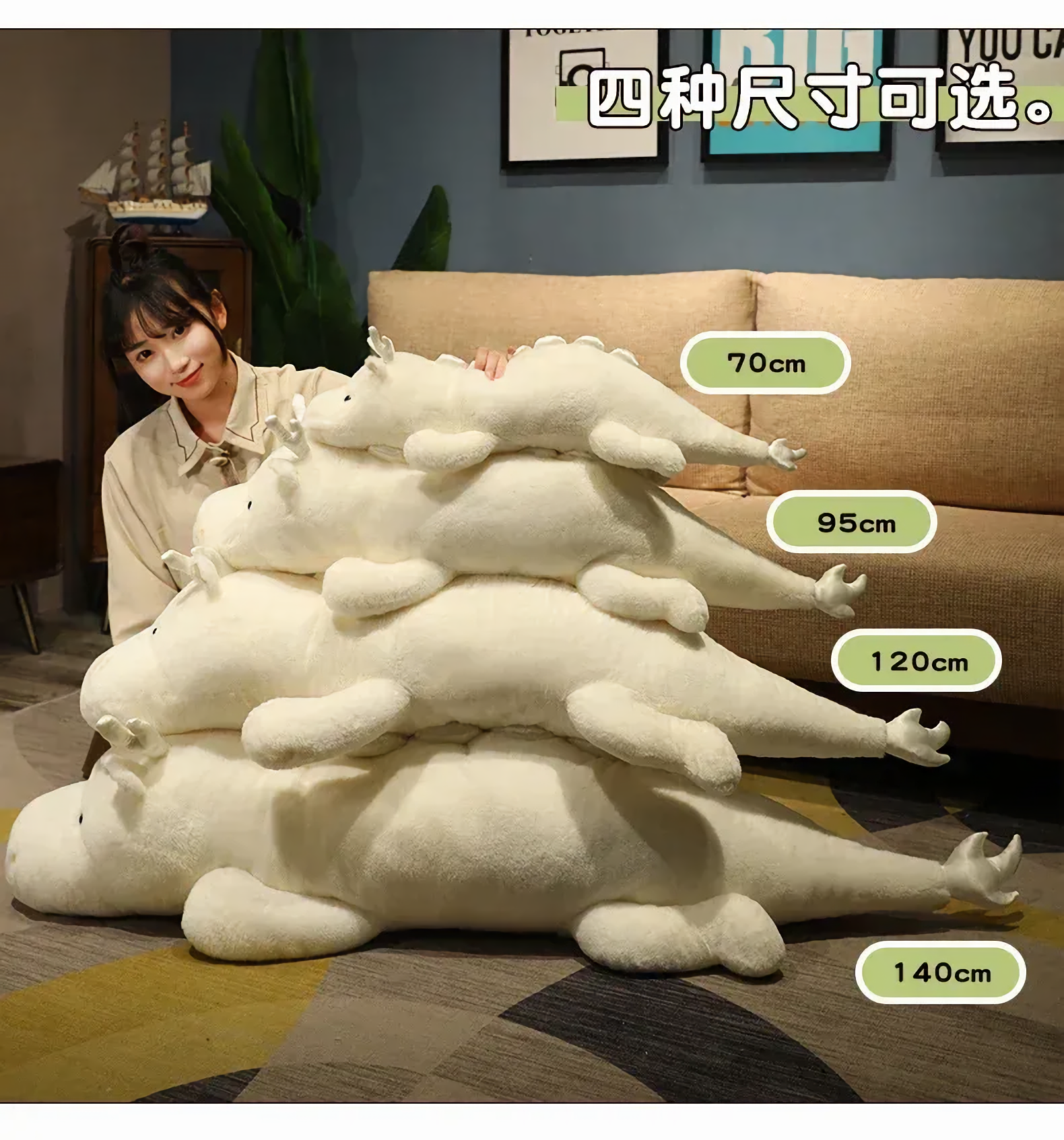 Woman sitting beside a stack of white and mint green dragon plush body pillows labeled with four lengths.