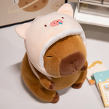 Capybara plush in a pink pig hood on a white table