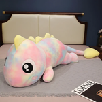 Rainbow Pink dinosaur plush body pillow in pink and yellow tie dye with big eyes on a bed