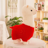 Red body alpaca plush with a white head and a stitched swirl on a table