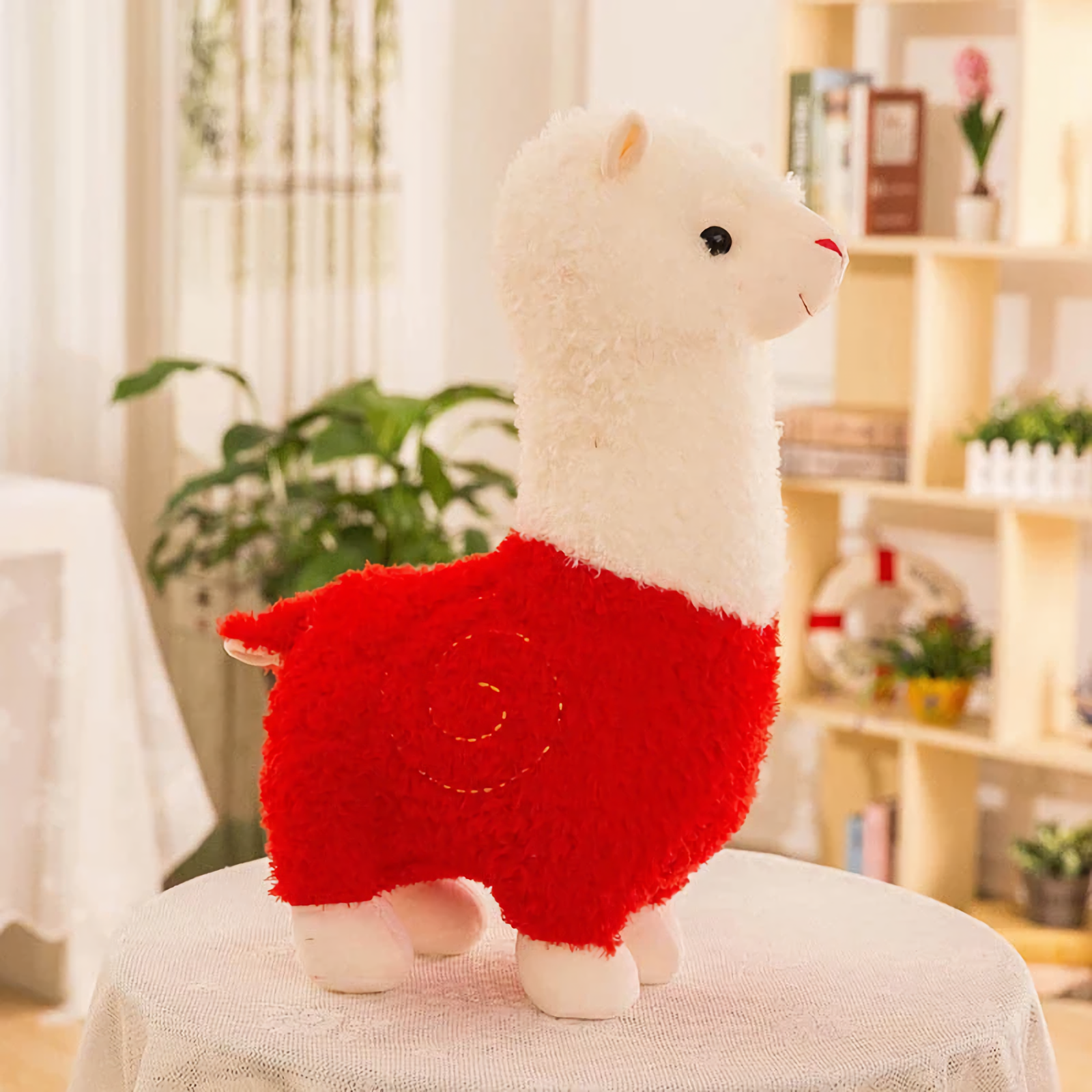 Red body alpaca plush with a white head and a stitched swirl on a table