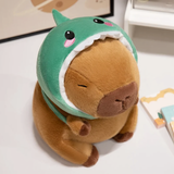 Capybara plush in a green dinosaur hood on a white table