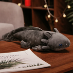 Gray axolotl plush with blue eyes and long gills on a wooden table