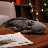 Gray axolotl plush with blue eyes and long gills on a wooden table