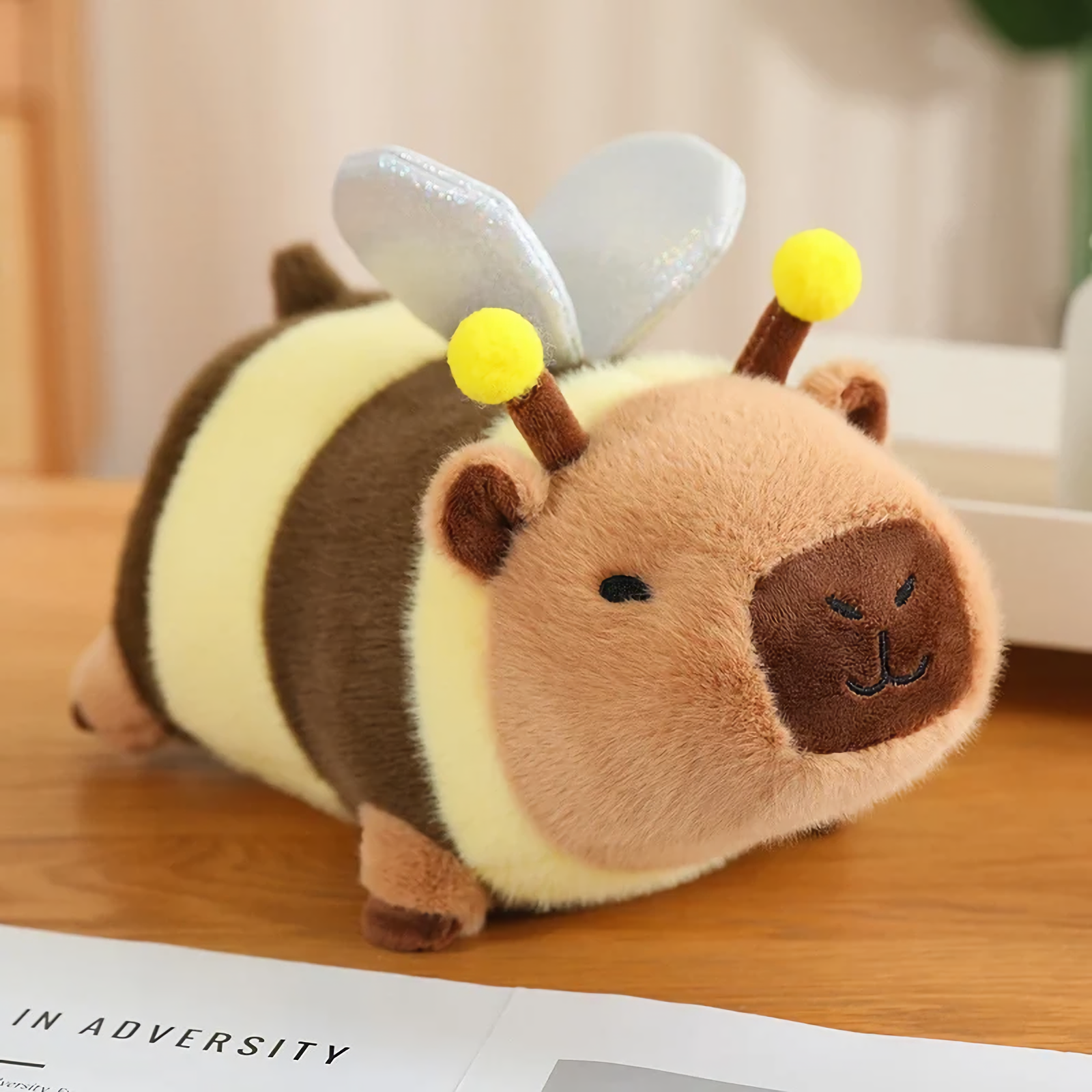 Capybara plush in a bee costume with striped body and wings on a wooden table