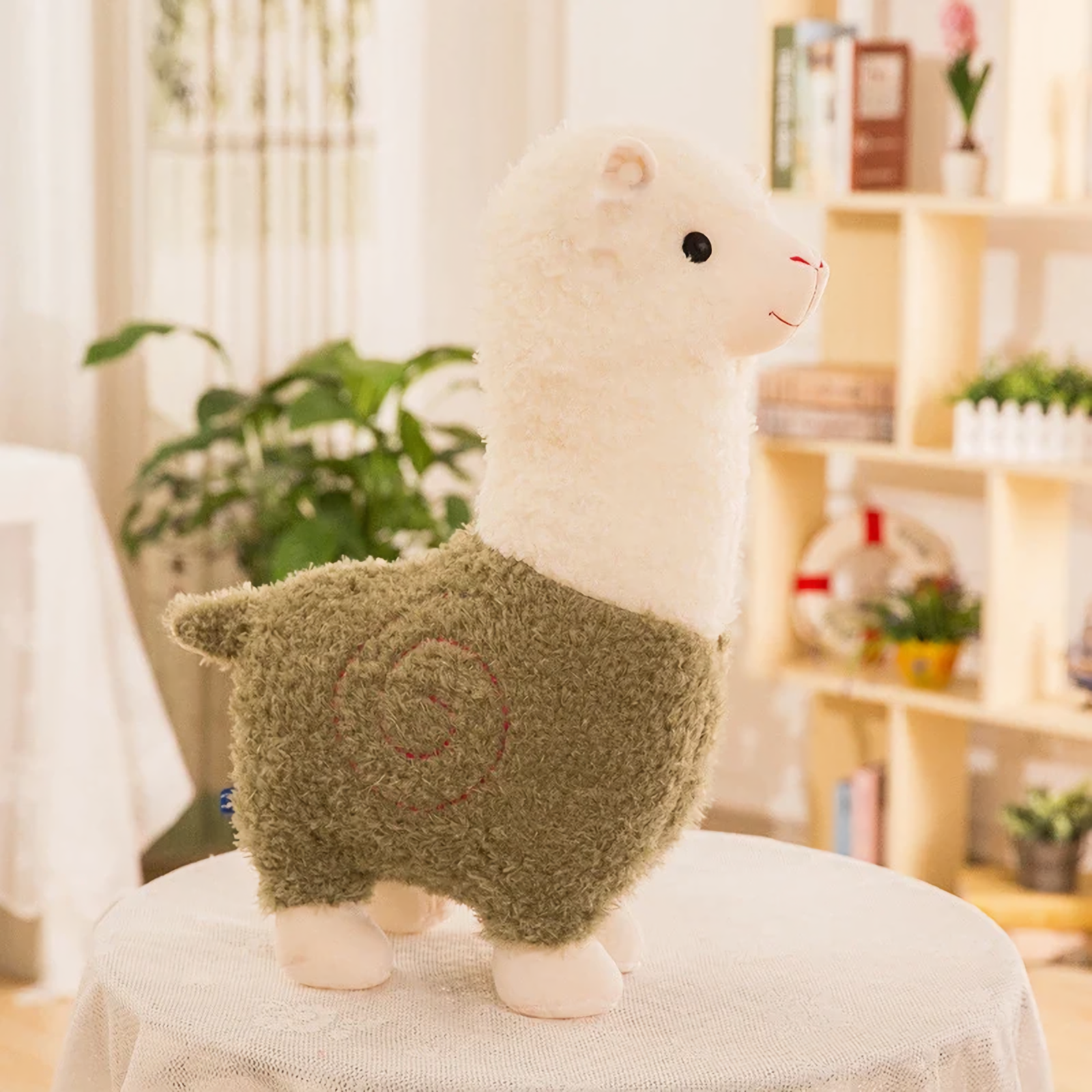 Green body alpaca plush with a white head and a stitched swirl on a table