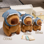 Size comparison of three capybara plushies in blue shark hoods marked 40cm, 25cm and 20cm