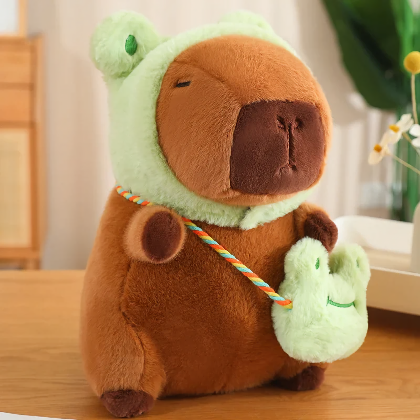 Capybara plush in a green frog hood with a frog mini bag