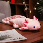 Pink axolotl plush with a light pink tail and gills on a wooden table