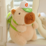 Brown capybara plush with a white cap and a green bag strap with a clip