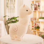 White alpaca plush with a red stitched swirl on its side on a table