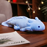 Blue axolotl plush with a light blue tail and feathery gills on a wooden table