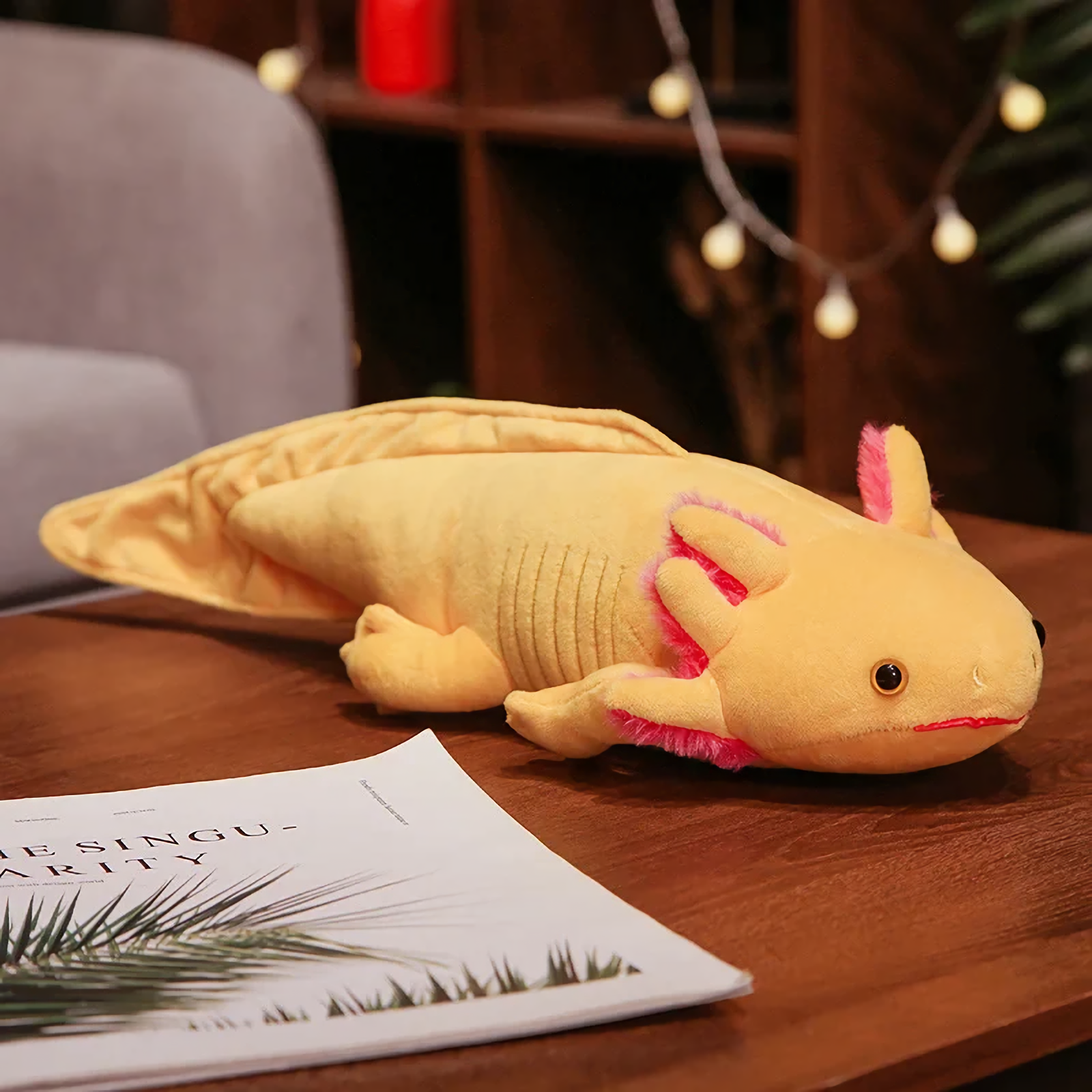 Yellow axolotl plush with pink gills on a wooden table