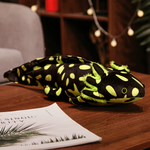 Black axolotl plush with bright lime green spots on a wooden table