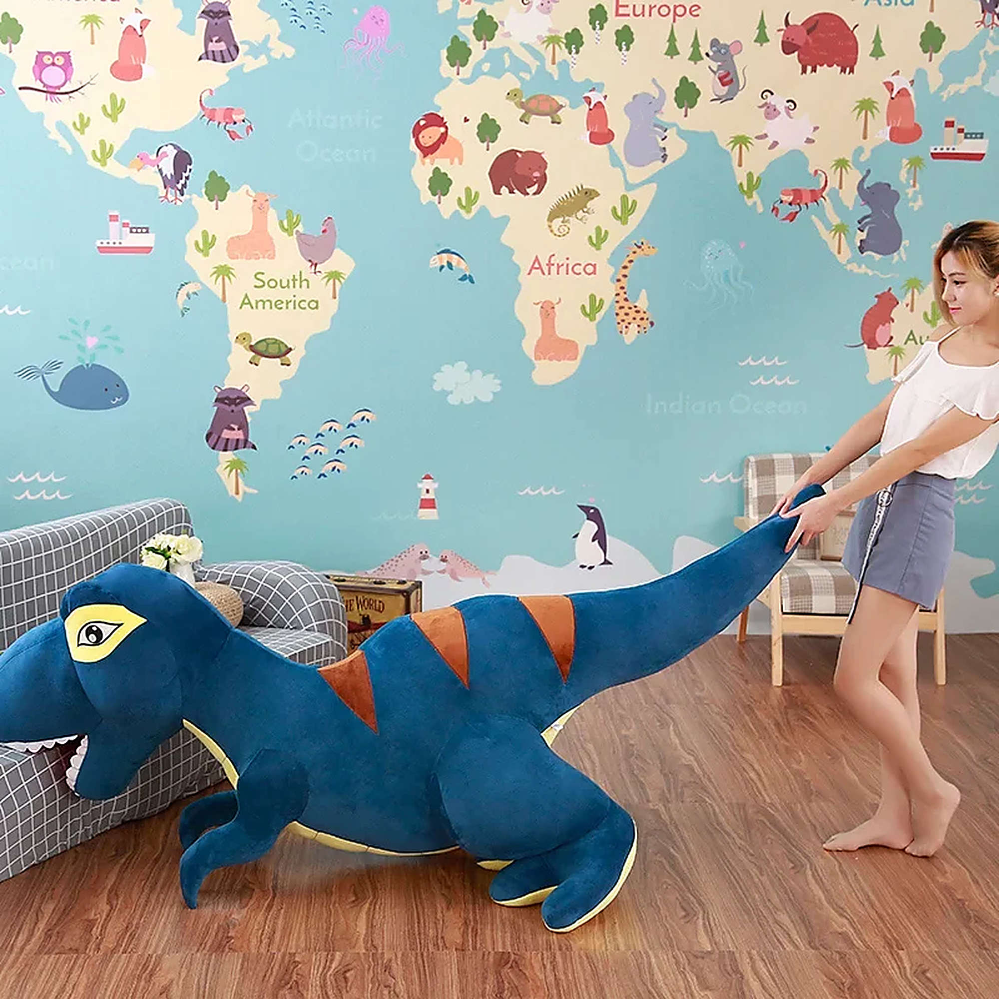 A person pulls a large blue dinosaur plush toy in a room with a world map mural on the wall.
