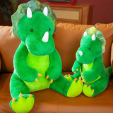 Two green triceratops plush toys, one large and one small, sitting on a brown couch.