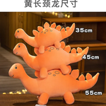 Three stacked orange dinosaur plush toys of varying sizes on a table.