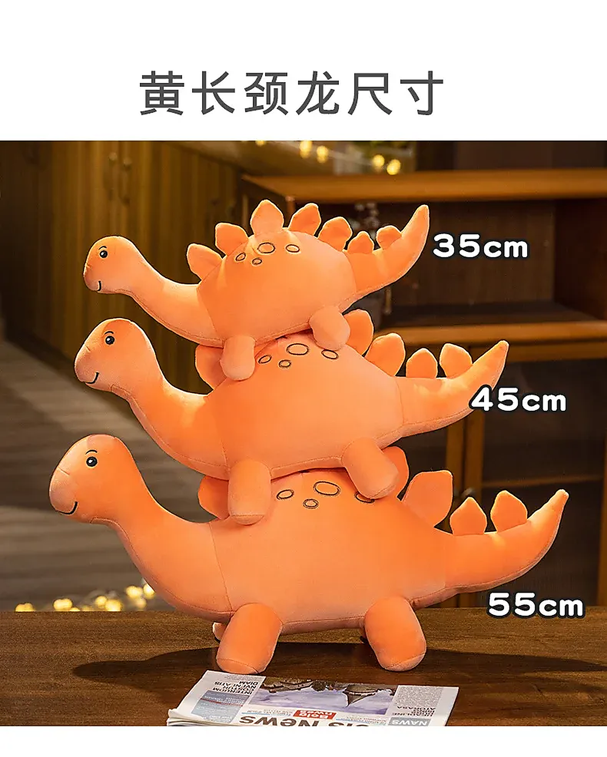 Three stacked orange dinosaur plush toys of varying sizes on a table.