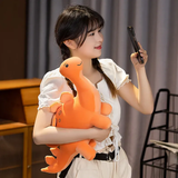 A person holds an orange dinosaur plush toy while taking a photo with a smartphone.