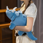 A person holds a blue triceratops plush toy, featuring soft fabric and cute details, against a blurred background.