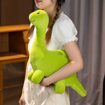 A person holding a green dinosaur plush toy with a smiling face and small details, wearing a white shirt.