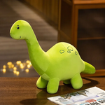 Green plush dinosaur toy with a smiling face and small spots, sitting on a wooden surface next to a newspaper.