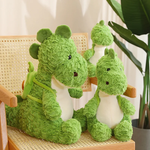Green dinosaur plush toys with textured fur, sitting on a chair, with one wearing a small avocado backpack.
