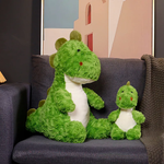 Green dinosaur plush toys, one large and one small, sitting on a dark sofa with a cozy blanket.