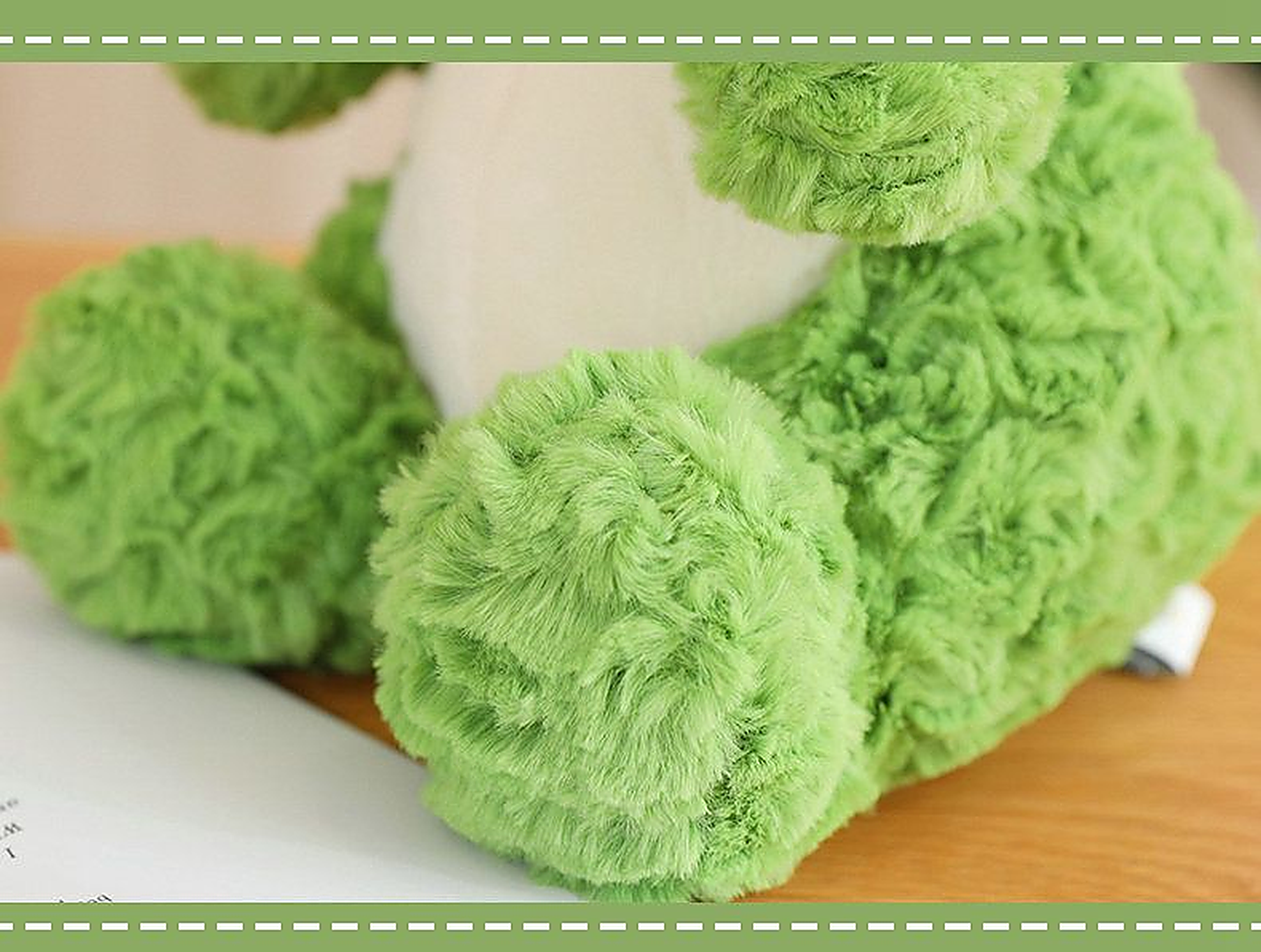 Close-up of a cute green dinosaur plush toy with soft, fluffy texture and round feet, resting on a wooden surface.