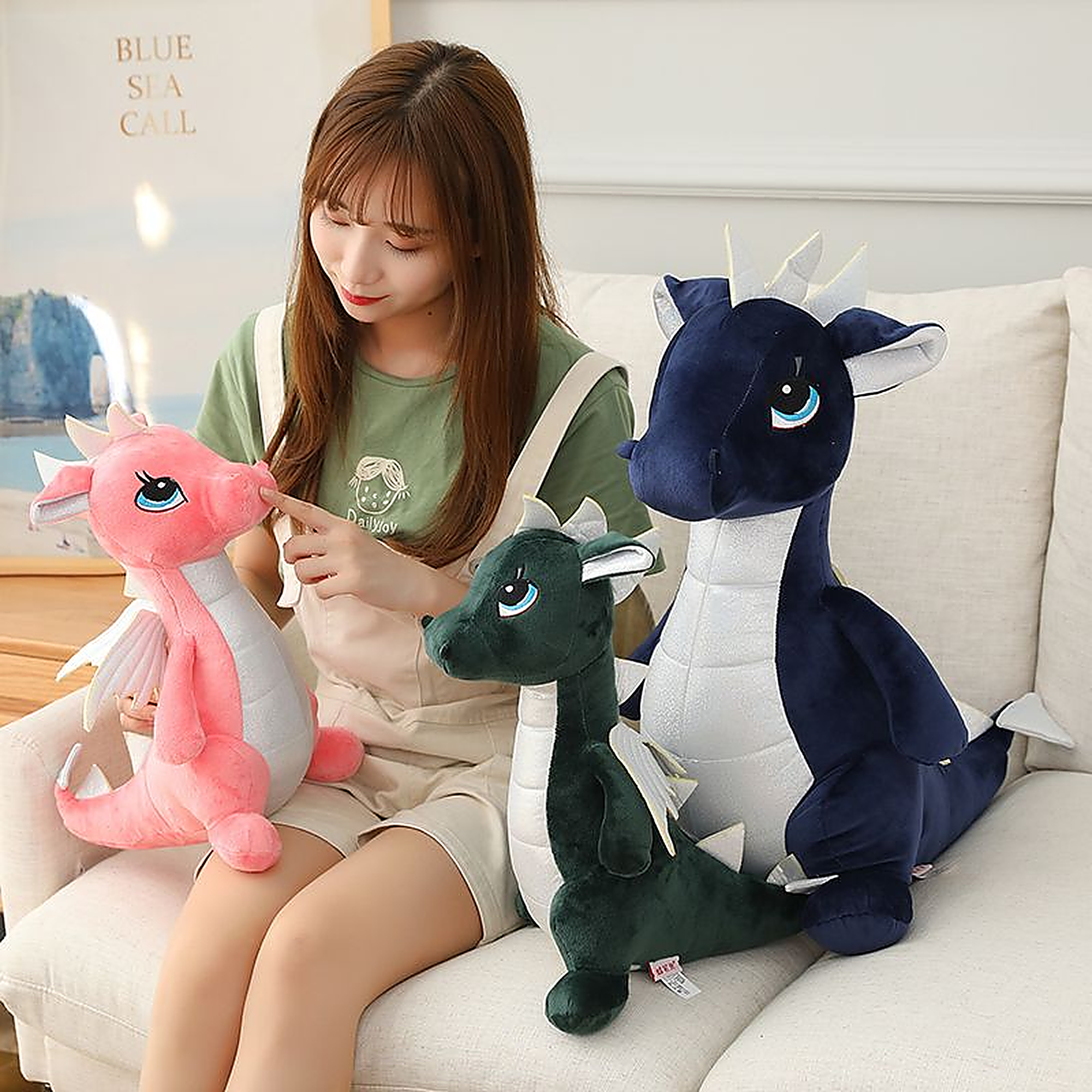A person interacts with three plush dinosaur toys in various colors on a sofa.