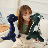 A person holds two plush dinosaur toys, one blue and one green, while sitting on a couch.