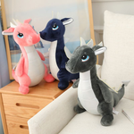 Three plush dinosaur toys in pink, blue, and gray colors sitting on a chair next to a wooden table.