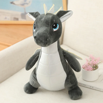 Gray and white plush dinosaur dragon toy with blue eyes and small wings, sitting on a light-colored surface.