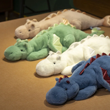 A row of colorful plush dragon toys with big wings, lying on a flat surface.