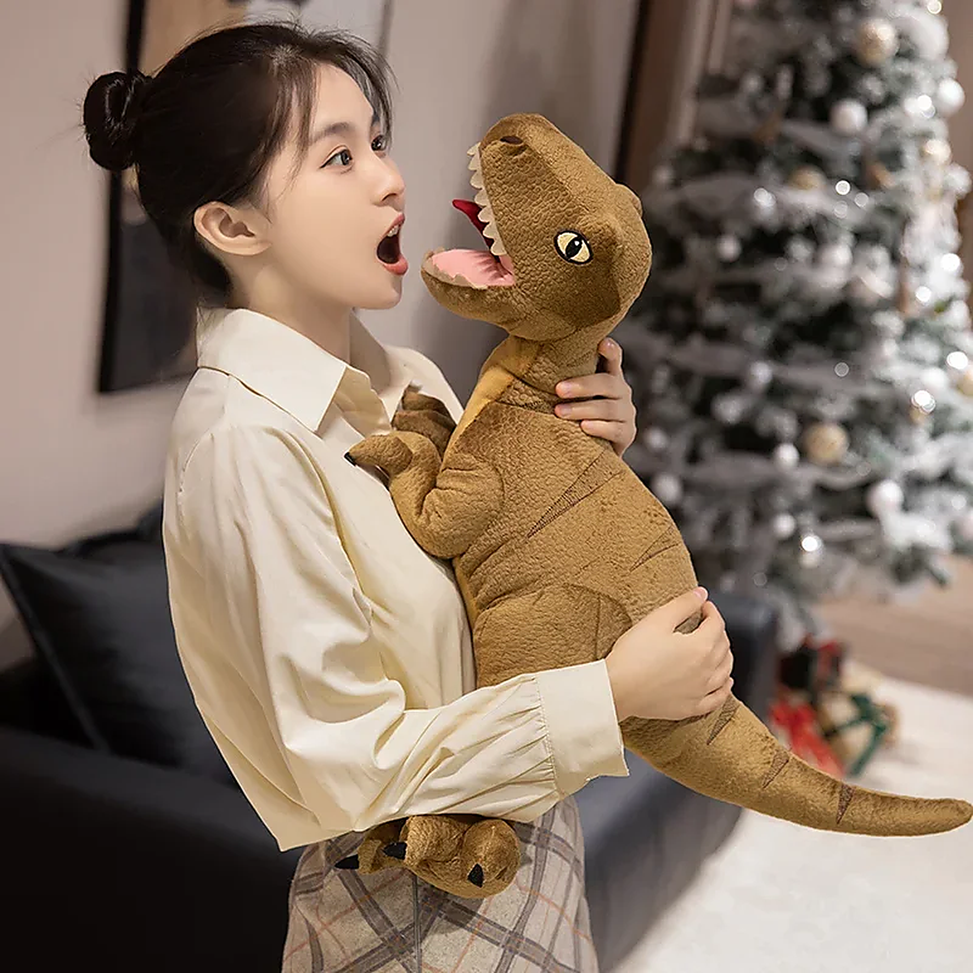 A person in a light shirt holds a plush dinosaur toy, expressing surprise in a cozy indoor setting.