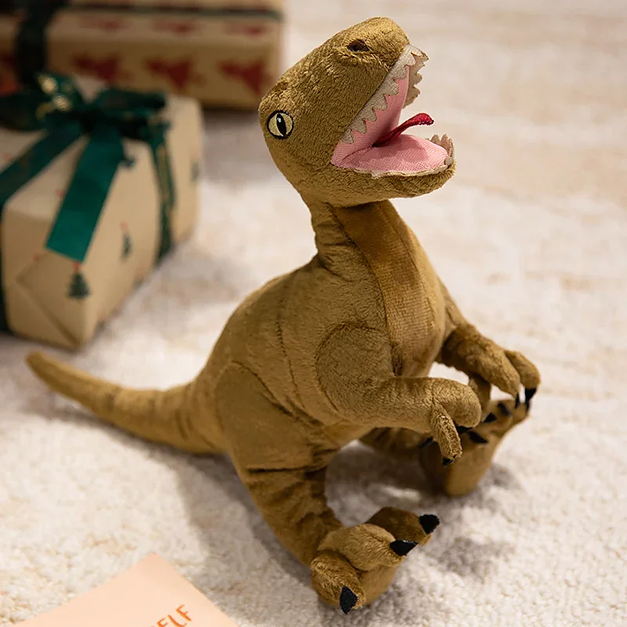 Plush dinosaur toy with a smiling face, sitting on a carpet near wrapped gifts.