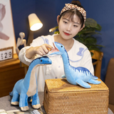 A person interacts with two blue dinosaur plush toys on a table next to a woven basket in a cozy room setting.